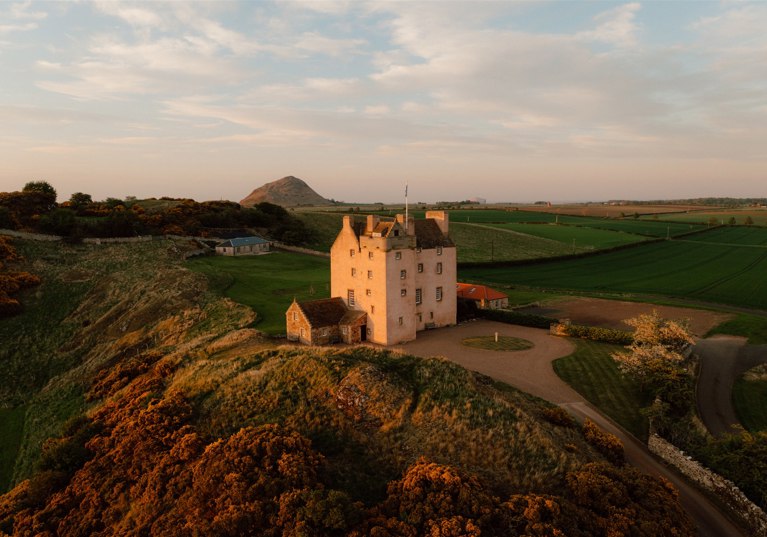 Aerial view of Fenton Tower wedding venue set within rolling East Lothian countryside at golden hour